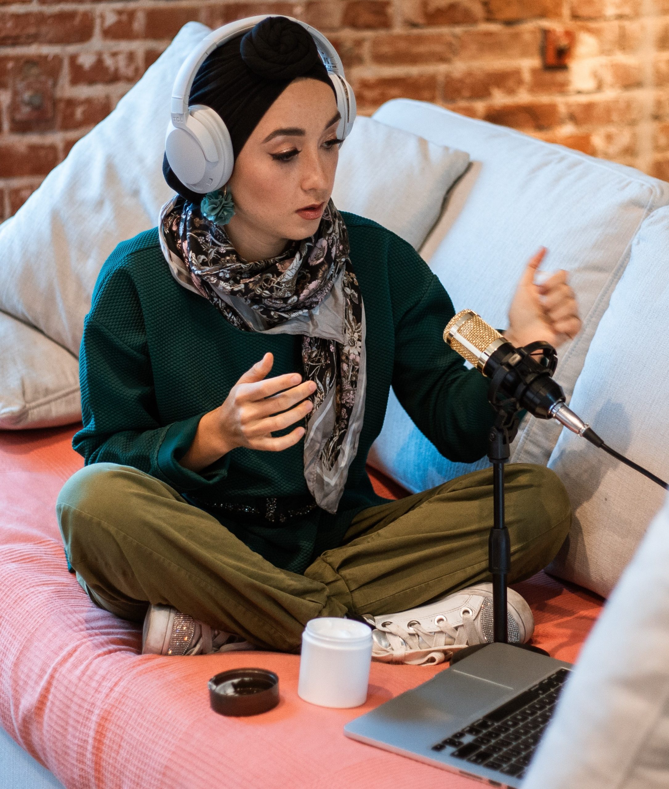 person wearing headphones and recording audio in front of laptop