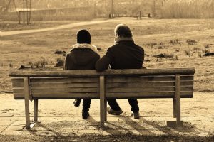 a couple sitting on a bench with their backs to the camera