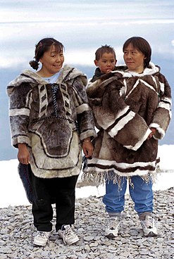 photograph of two Inuit women wearing traditional outerwear. One is holding a child.