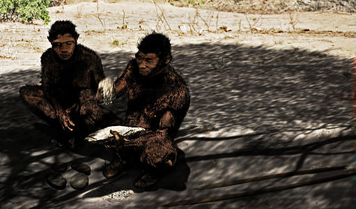 painting of two Homo erectus individuals; one is making an Acheulean handaxe