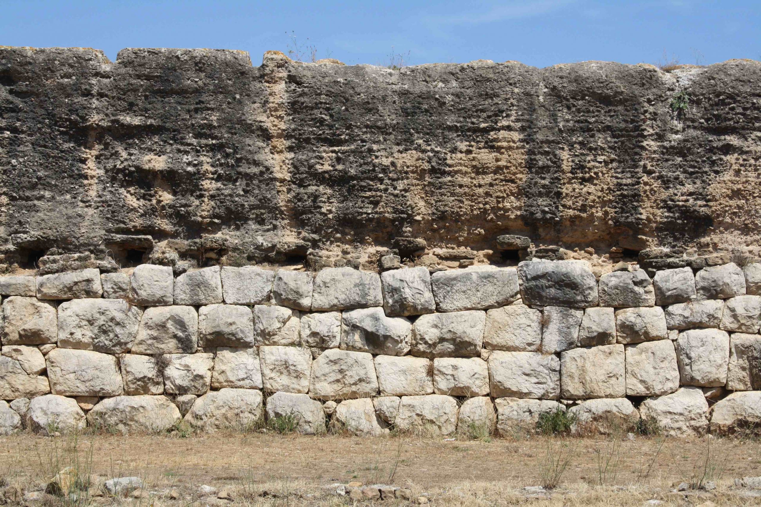 Wall with large stone blocks on bottom, and weather word but still intact concrete on top