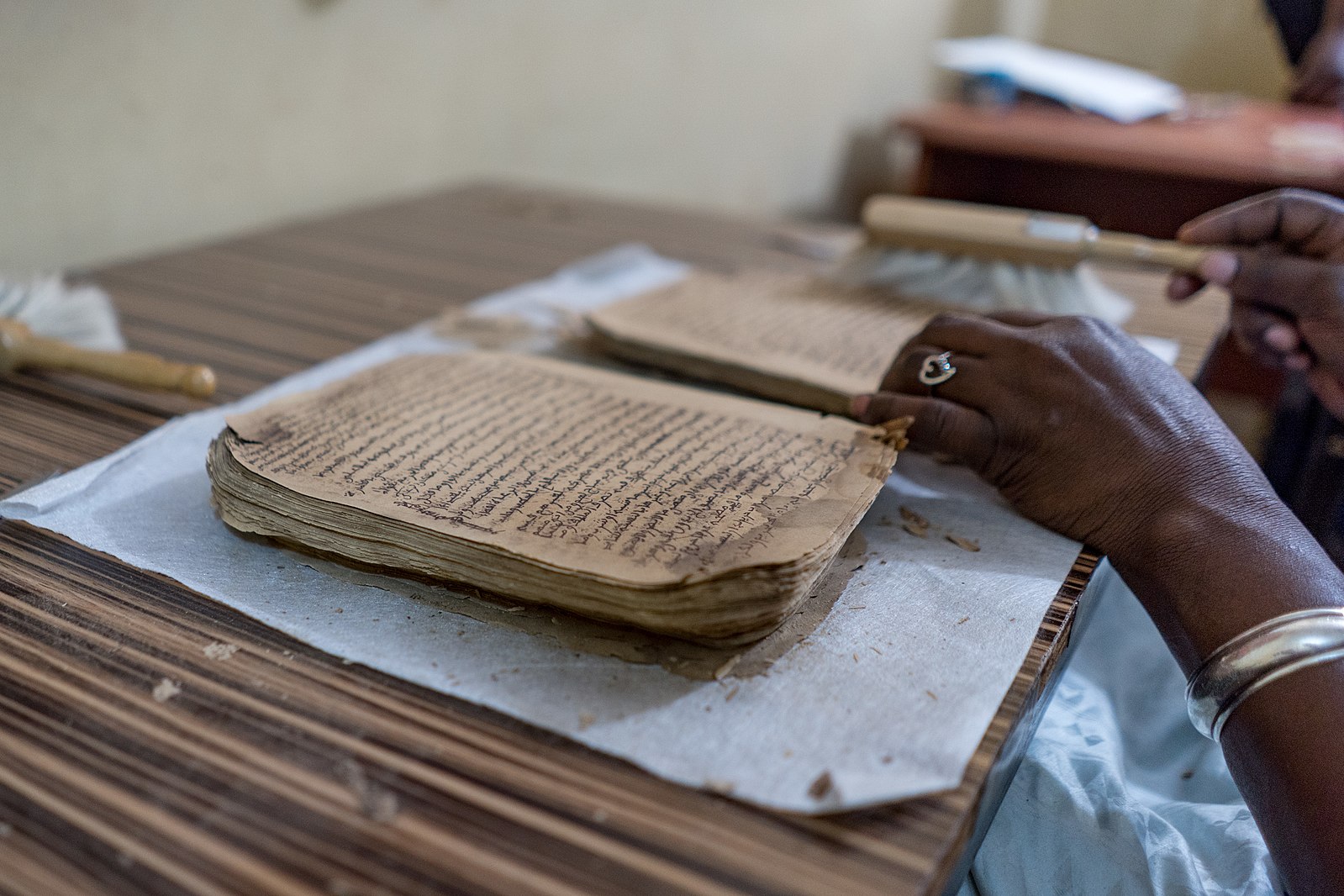 Old manuscript being worked on by preservationist with a brush