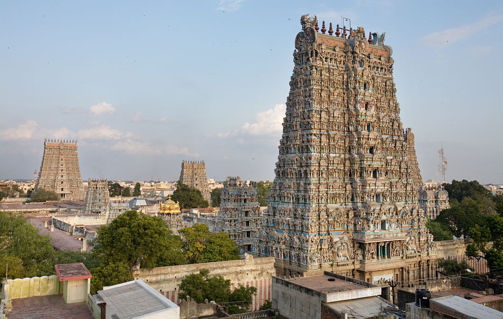 Large plain with several tall temples. Nearest temple has numerous elaborate sculptures on all the walls and entrance.