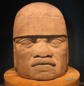 Large stone head of man with headdress and grim face