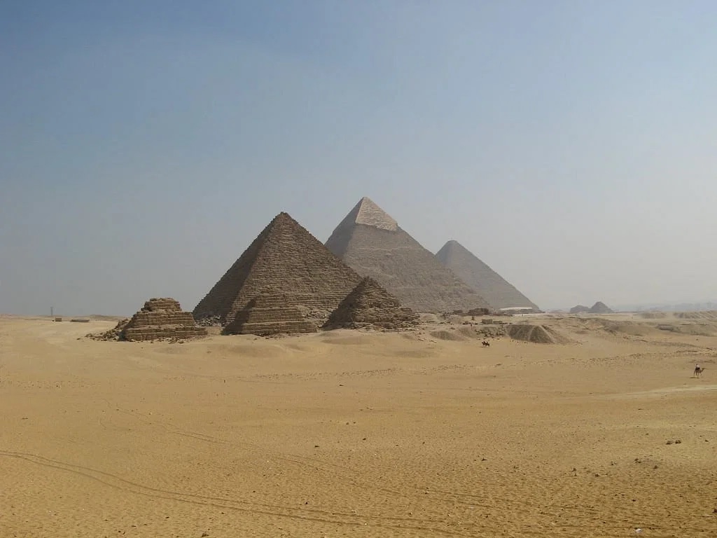 Barren desert with three massive pyramids, and 5 smaller pyramids surrounding them.