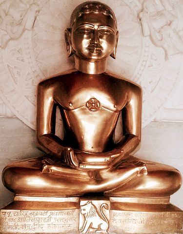 Statue of person sitting in meditation pose, with script on the base below.