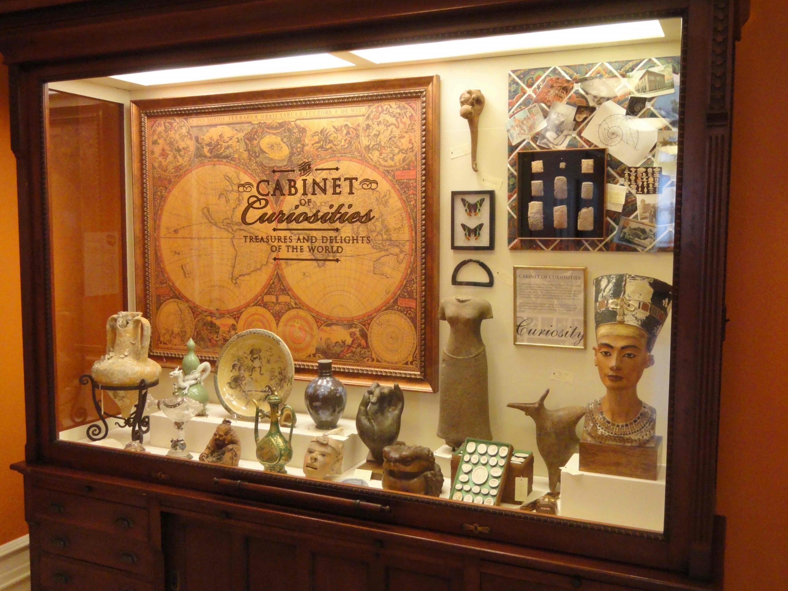 Cabinet with large glass window containing diverse assortment of artifacts and statues.