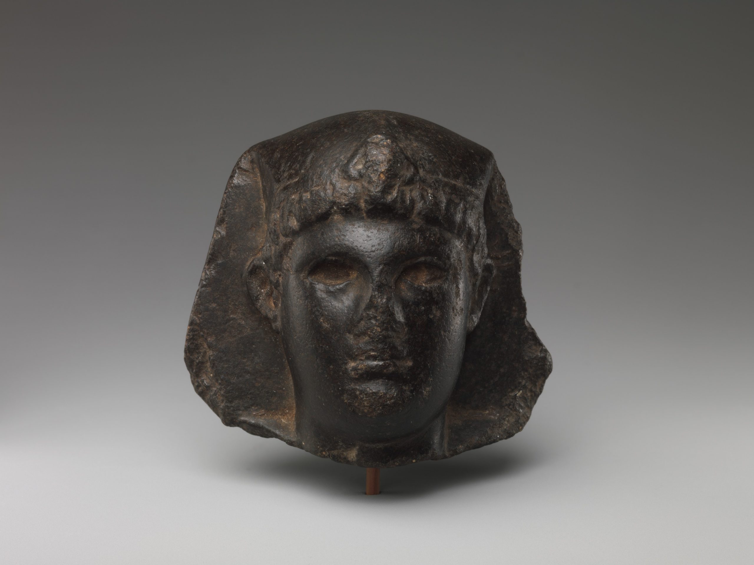 Statue of a Ptolemaic king's head with both Greek and Egyptian features, specifically, Greek hair and Egyptian headdress.