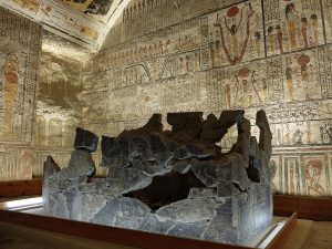 Large room with Egyptian hieroglyphics and images covering all the walls and the ceiling, with partial stone tomb in the center