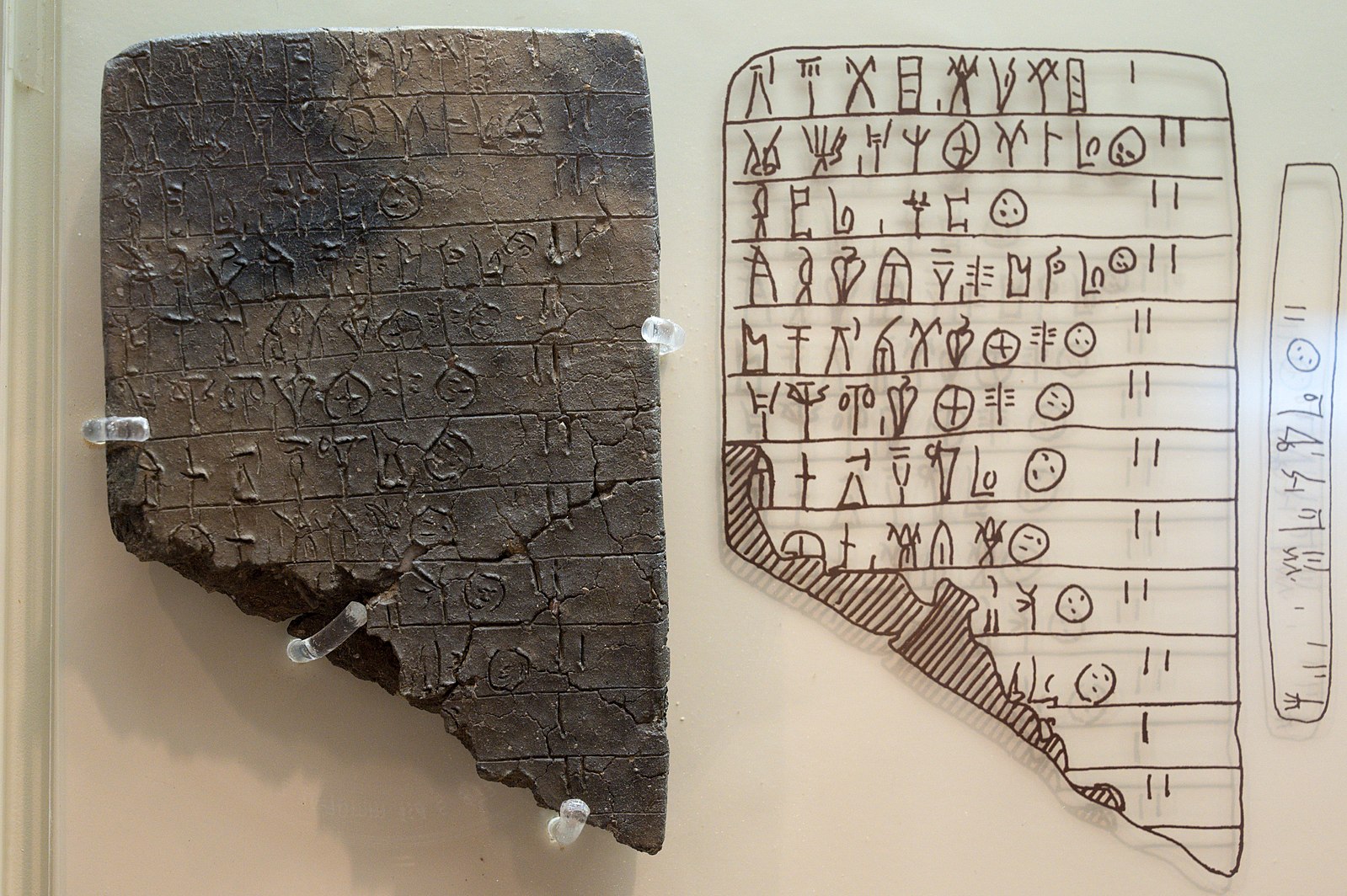 Partial stone table with ancient inscriptions on it, next to it is drawn outline of those inscxriptions for easier viewing