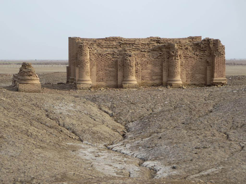 Ruins of Mesopotamian temple, set in surroundings of desert and eroded soil