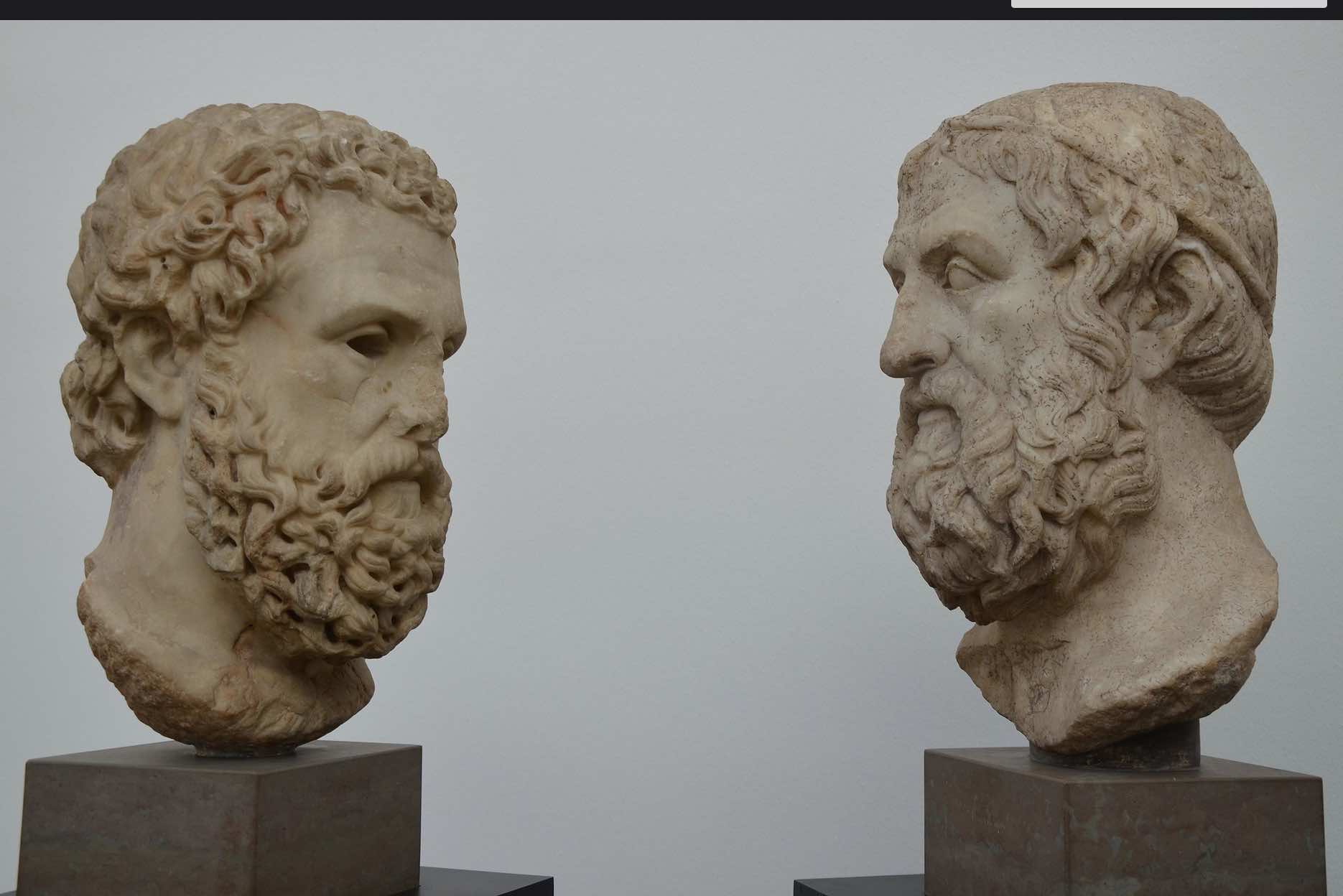 Two sculpted heads of Greek men with beards and solemn expressions