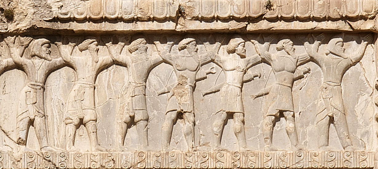 Stone wall carving showing row of men with beards, arms upraised. They are wearing swords and daggars.