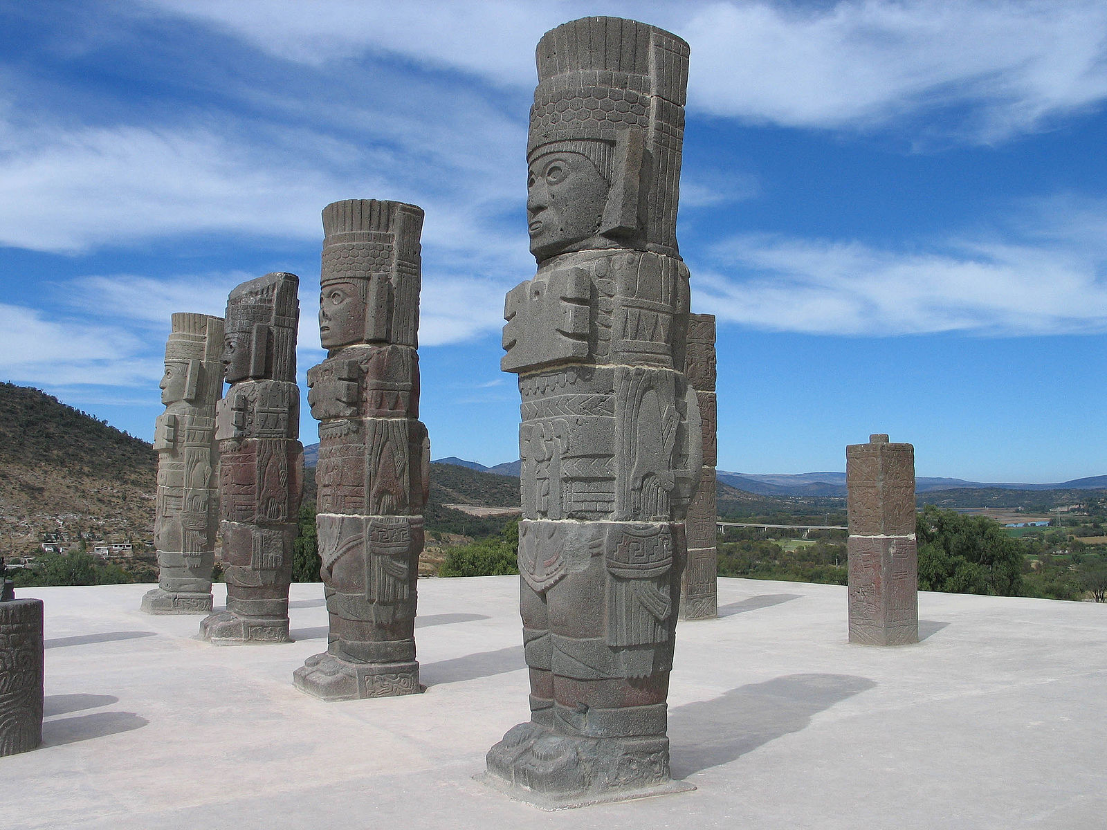 Several large standing statues with images cut into the stone, and faces with different expressions, wearing elaborate headresses