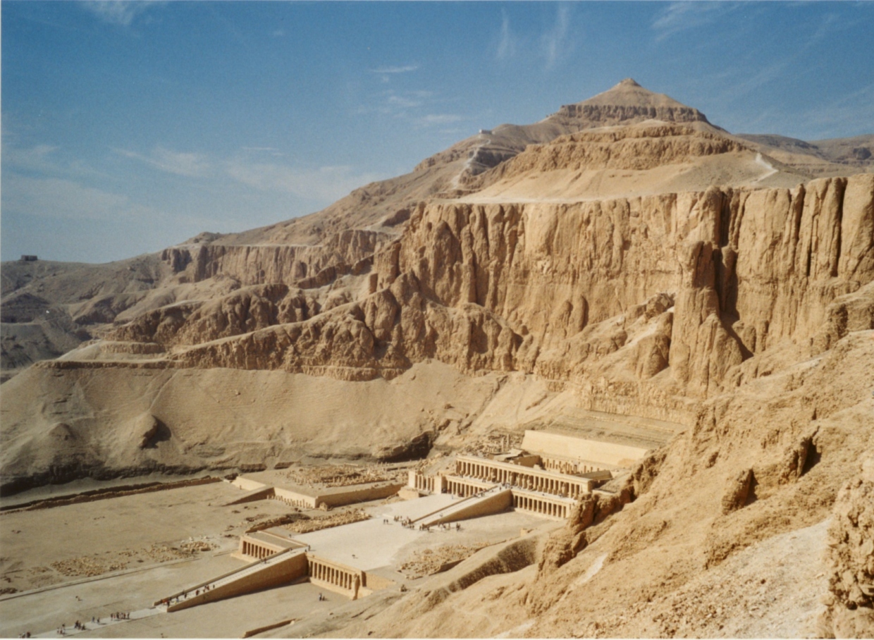 Barren hillside with large tomb buildings and entrance to the hill on side