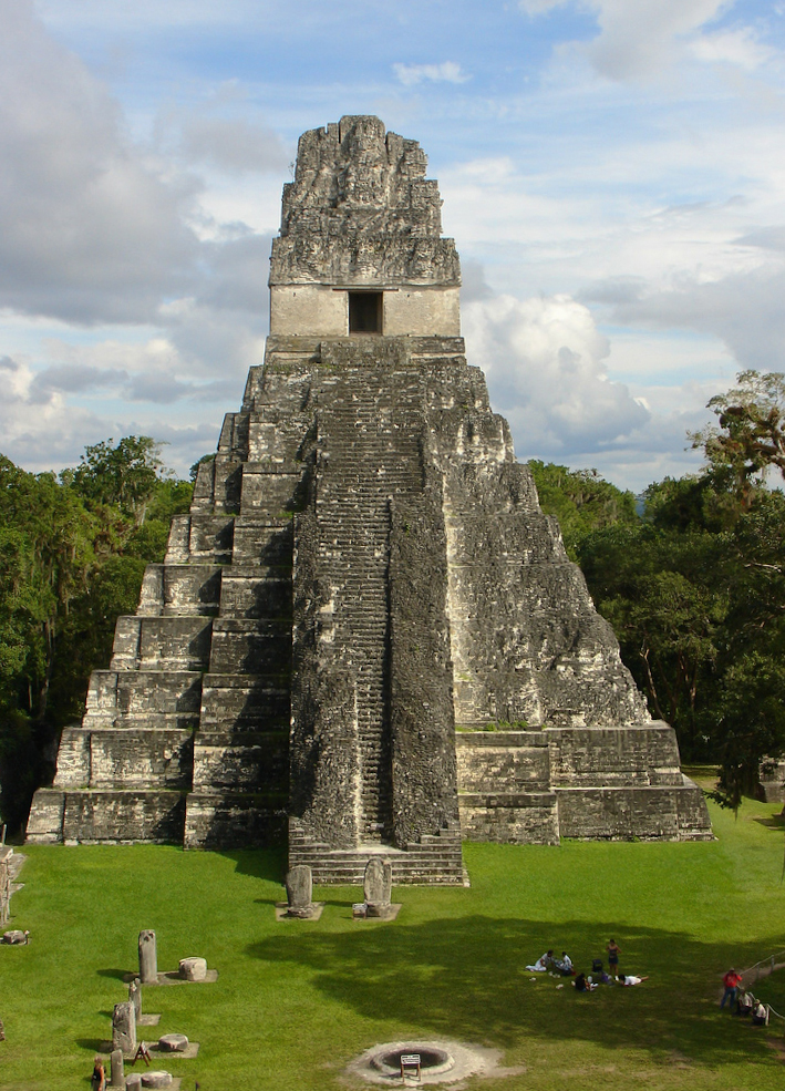 Massive stone temple with high, steep stairs leading to top room, surrounded by jungle