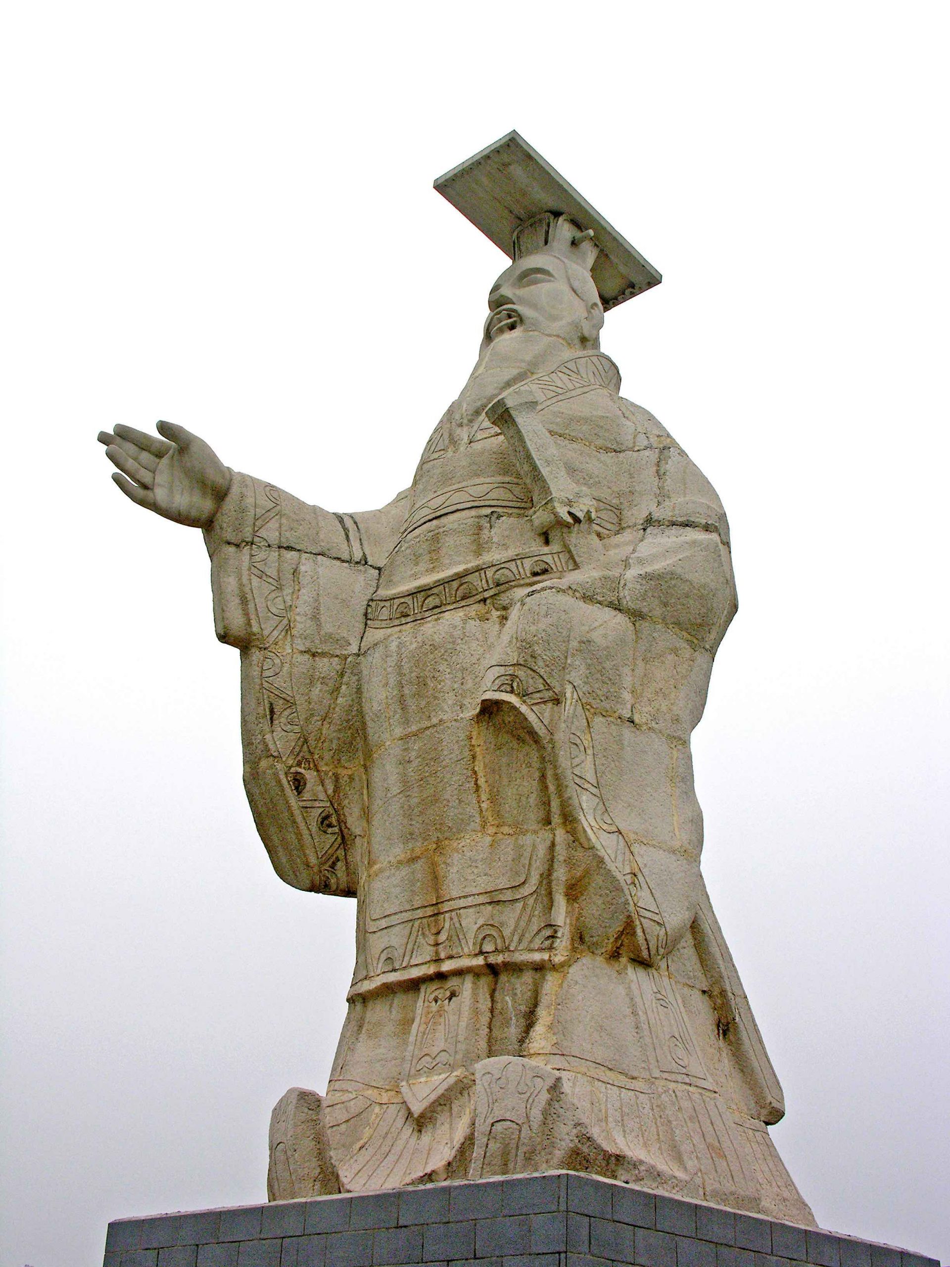 Statue of ancient Chinese man in traditional clothes, with one hand over a sword, the other reaching out