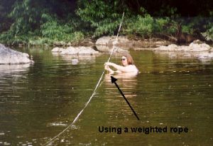 Technician wading chest deep in a river.