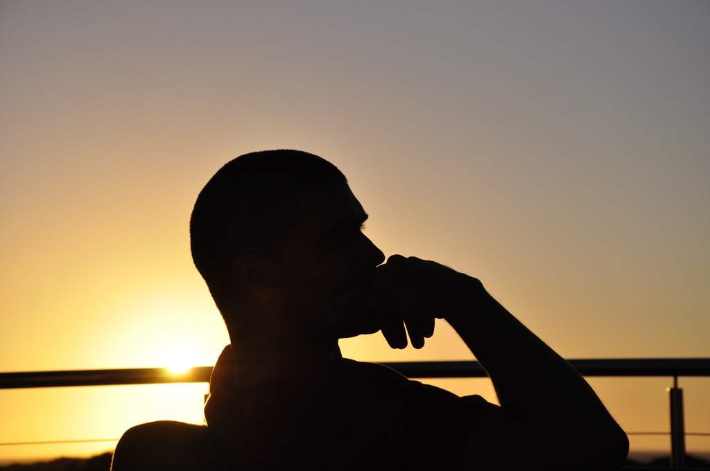 A man sitting down in "The Thinker" pose.