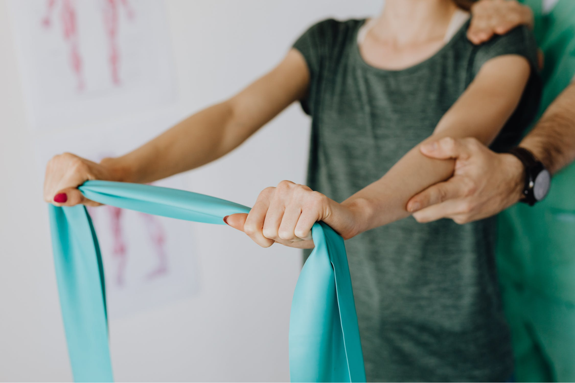 A patient stretching a resistance band with a healthcare professionals support