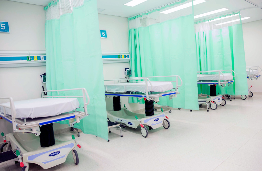 A row of stretchers separated by curtains in a healthcare facility.