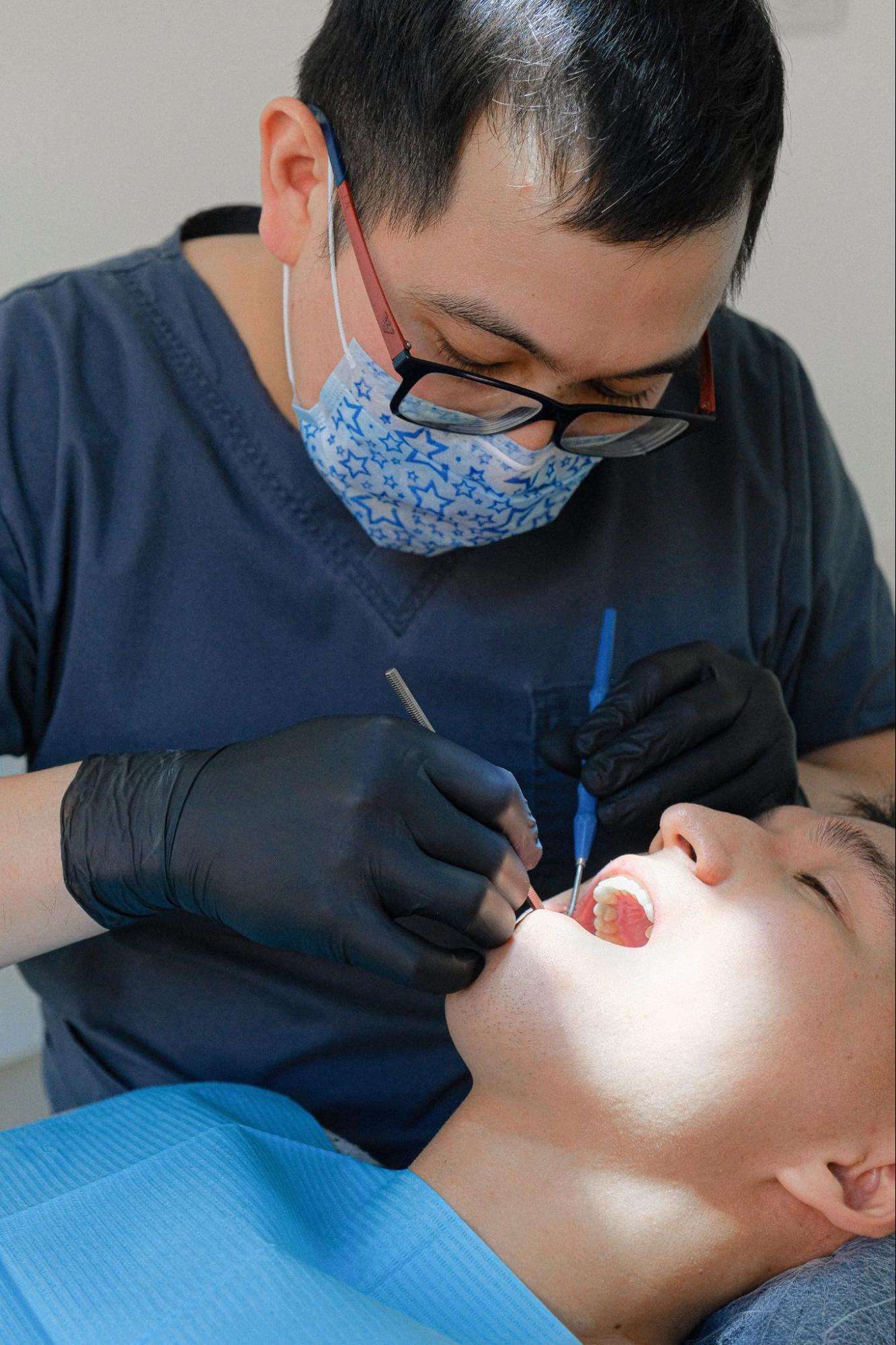 Dental assistant looking at the surfaces of a patient’s teeth.