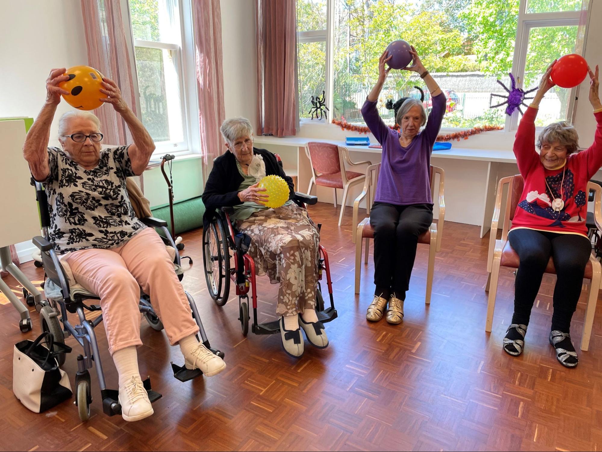 Four elderly women playing with balloons