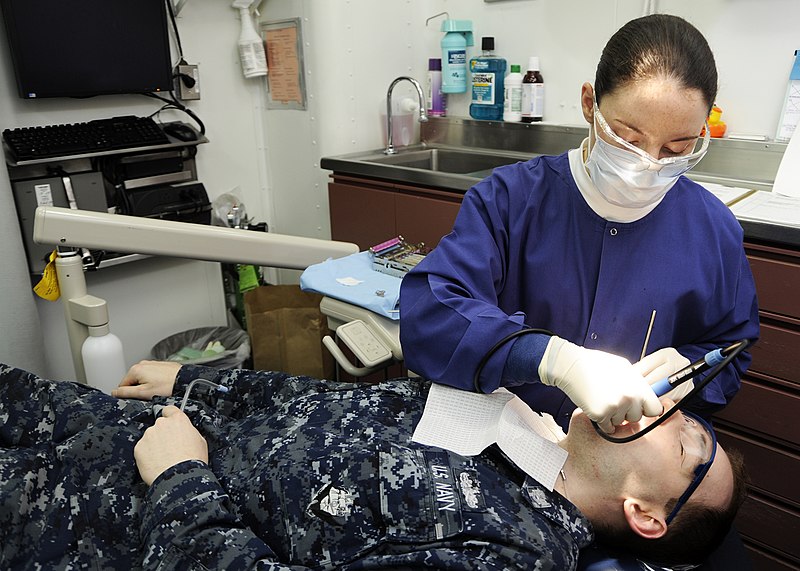 Dental health professional performing a routine cleaning on a patient.