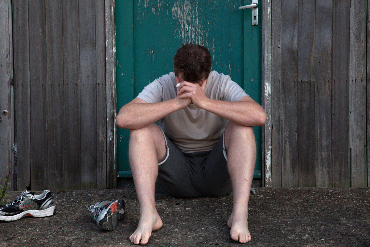 Person sitting with his shoes off, head down withdrawn