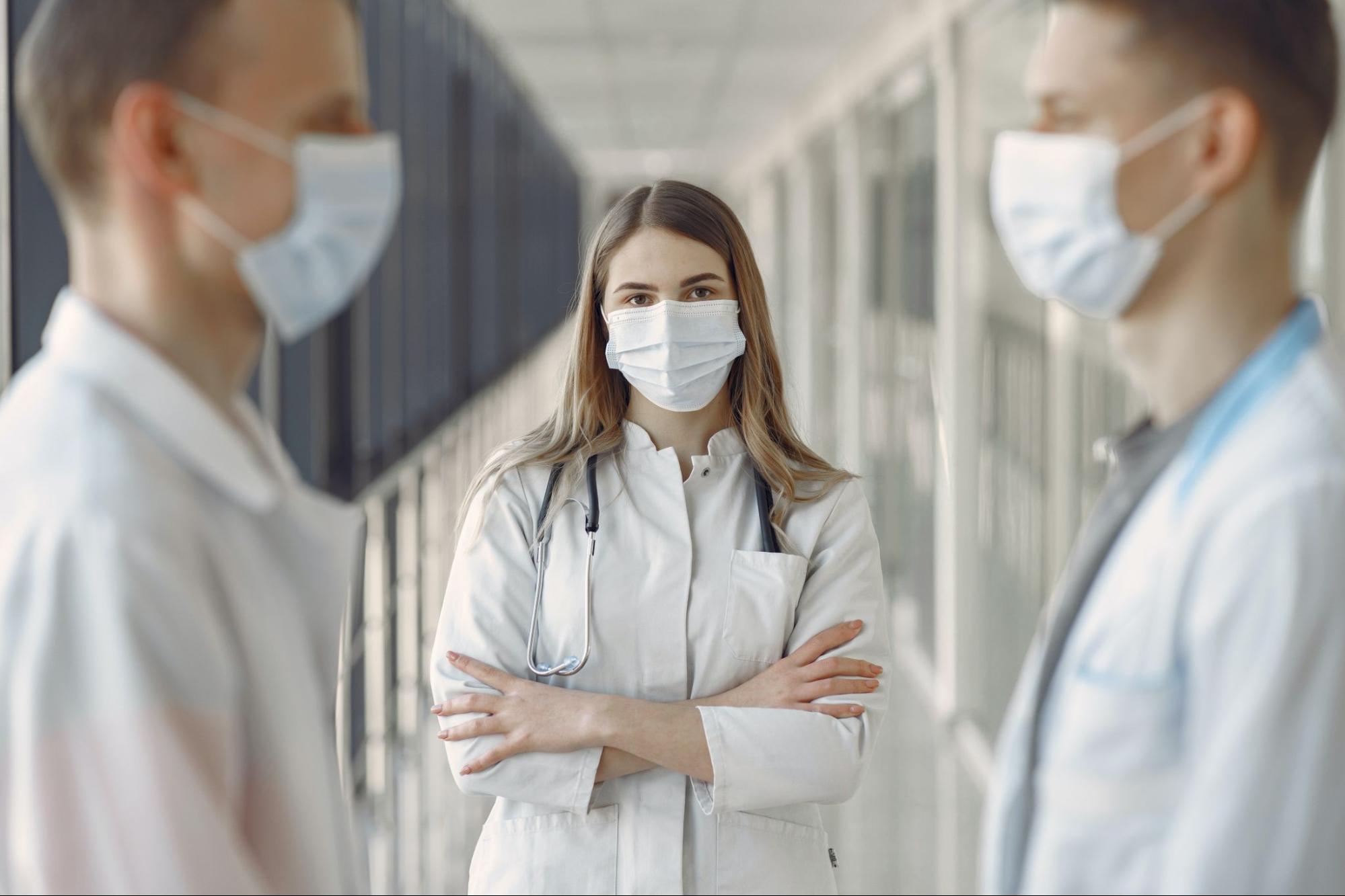 Two male doctors are talking to one another while a female doctor looks on