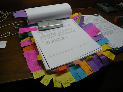 a stack of papers with color coordinated sticky notes hanging out of the sides