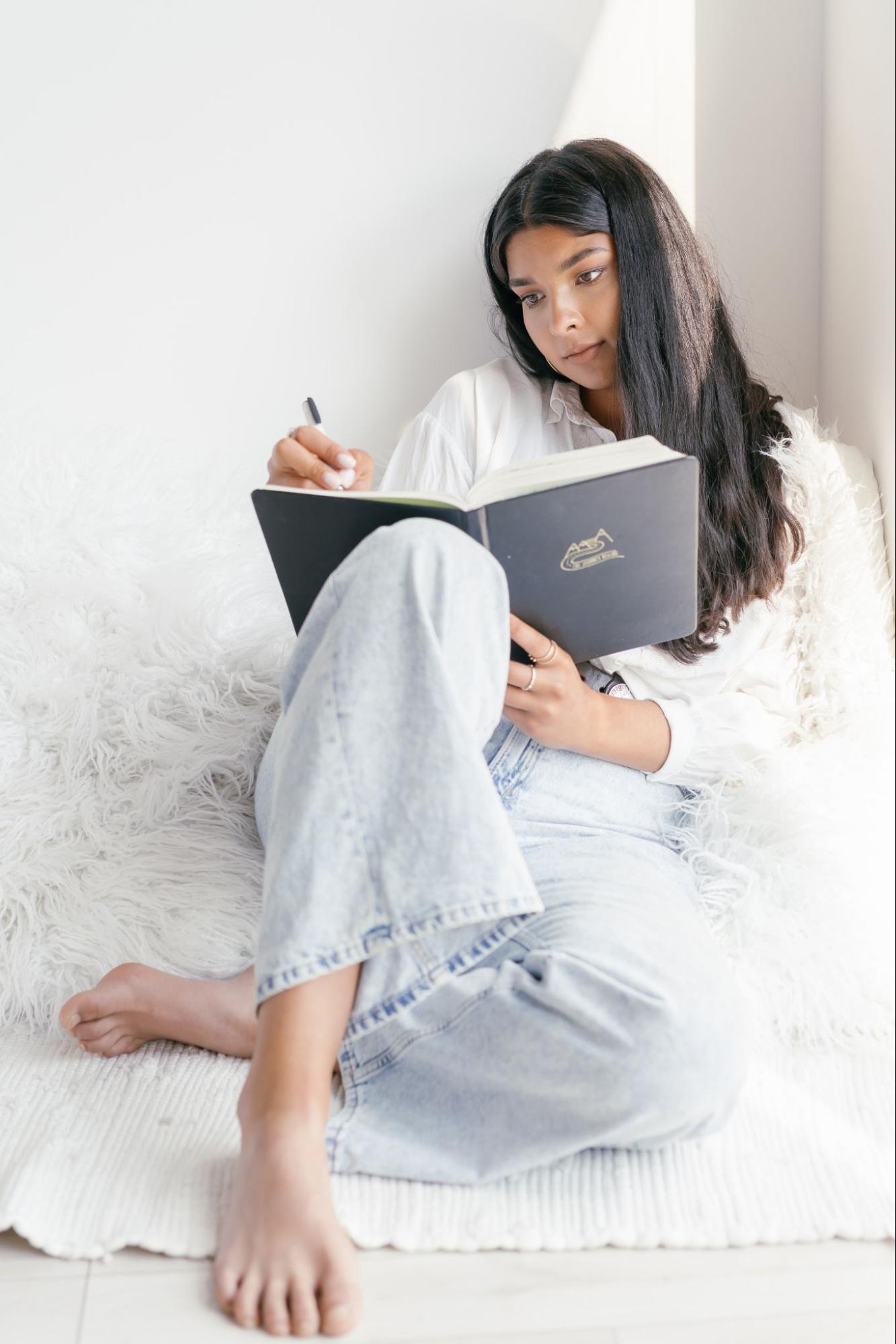 A young woman is reading and making notations in a book