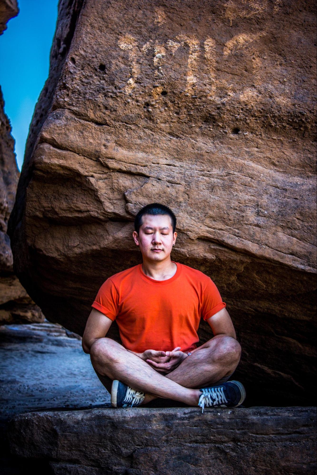 A man sitting with his eyes closed while he meditates