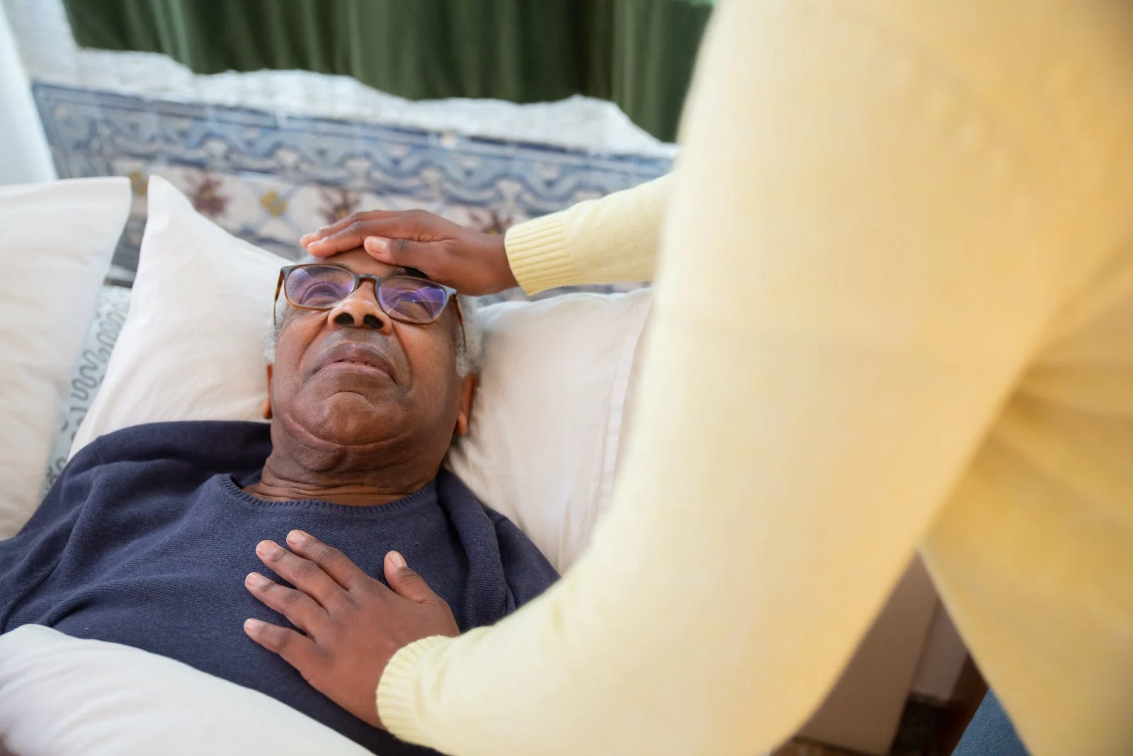 Healthcare professional touching a patient’s chest and forehead