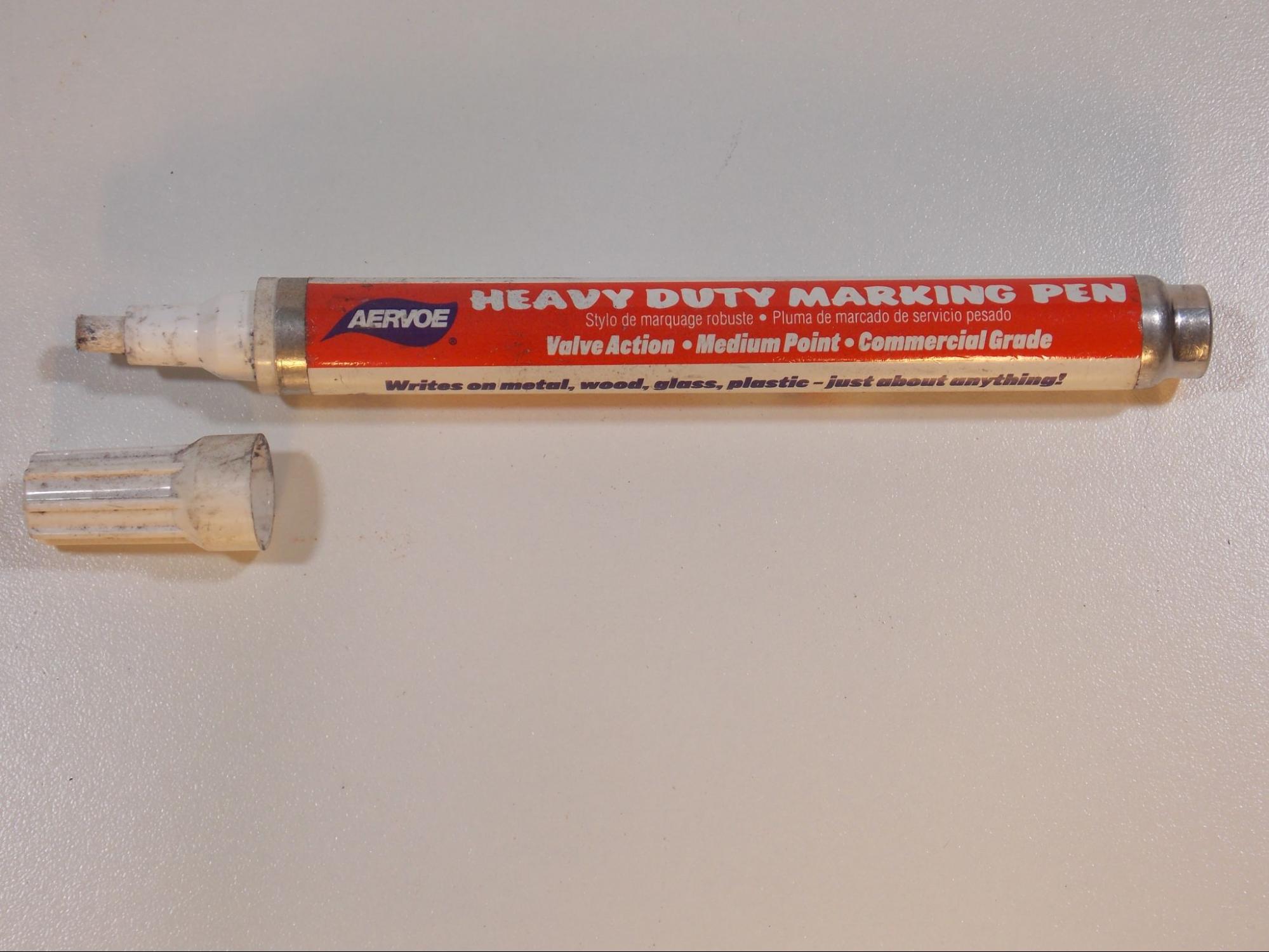 A paint pen marked heavy duty marking pen, medium paint, commercial grade. The white cap indicates that the paint color is white.