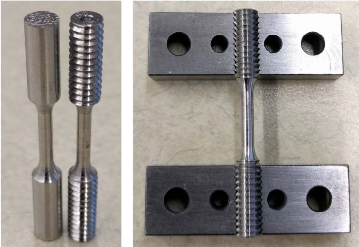 Tensile Test Specimens, which are cylindrical, made of a smooth metalsurface and are about 3 inches long and have 3 segments. The first and third segments are slightly wider and taper to the middle segment which is narrow. The specimen before being machined (on the left) has no ridges; it is smooth. The specimen on the right, after machining,has grooves on the first and third segments. The image on the right is the machined specimen in the holder in preparation for testing. The holder is two metal bars with four holes in each bar. The specimen rests on the two metal bars with the grooved ends on the bars and the center part of the specimens is inbetween the bars.