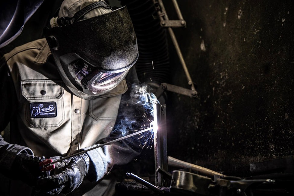 A welder in a comfortable welding position makes a practice weld using SMAW.