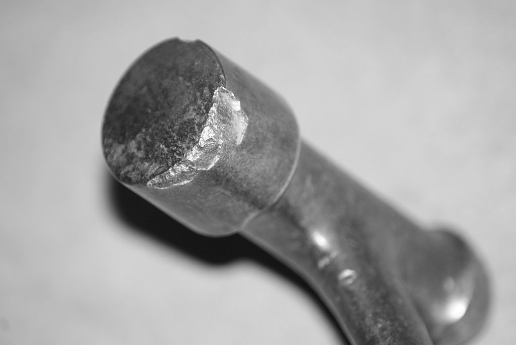 Close up view of a hammer face that has several pieces missing due to chipping of the edges.