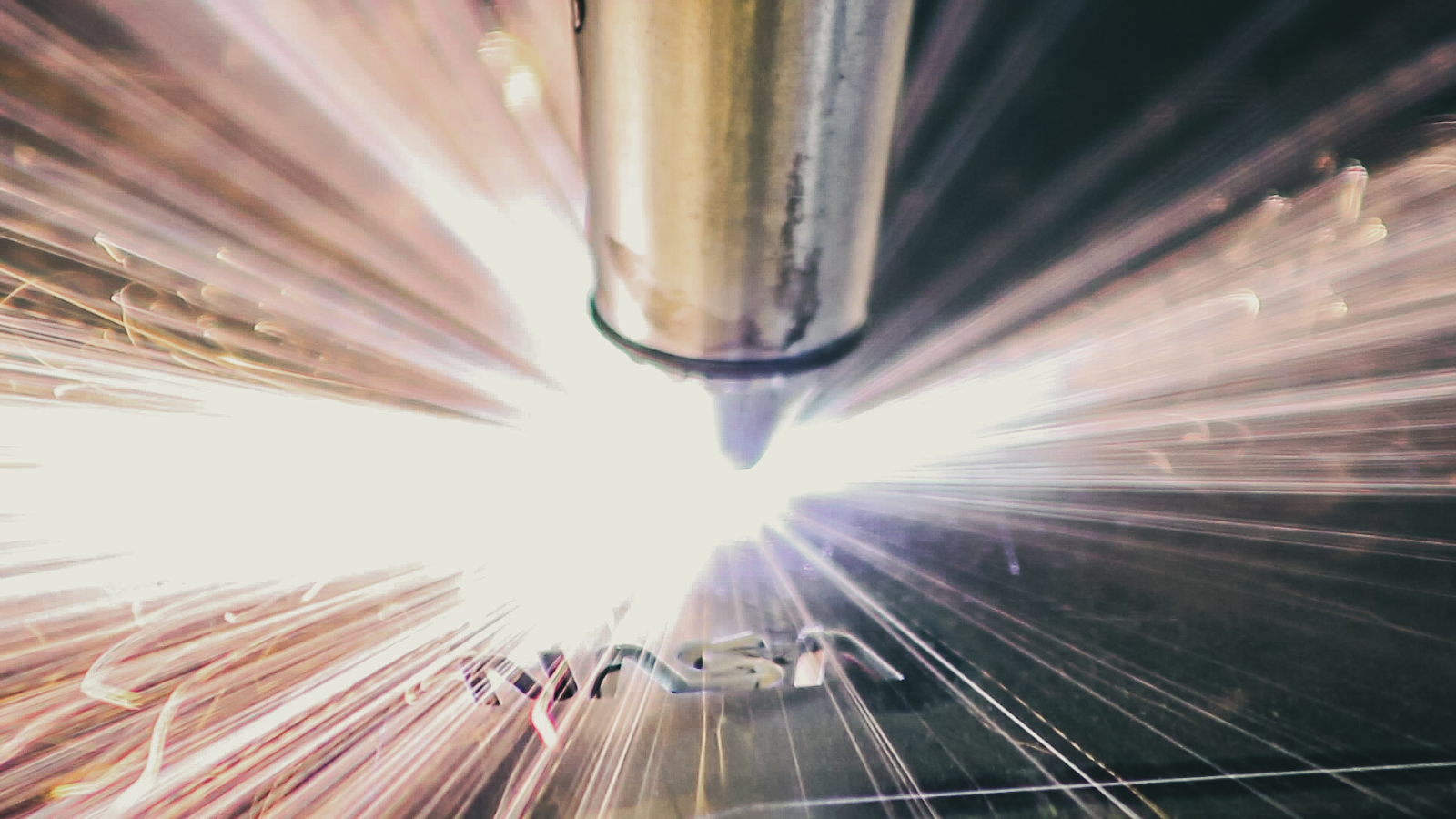 CNC plasma cutting something for NASA. A close up photograph of the tip of a welding torch throwing off sparks as it cuts into a piece of metal.