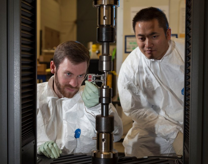 Tensile Test being conducted by technicians, one is holding a tensometer to measure the strain. The image is described in the text surrounding it.