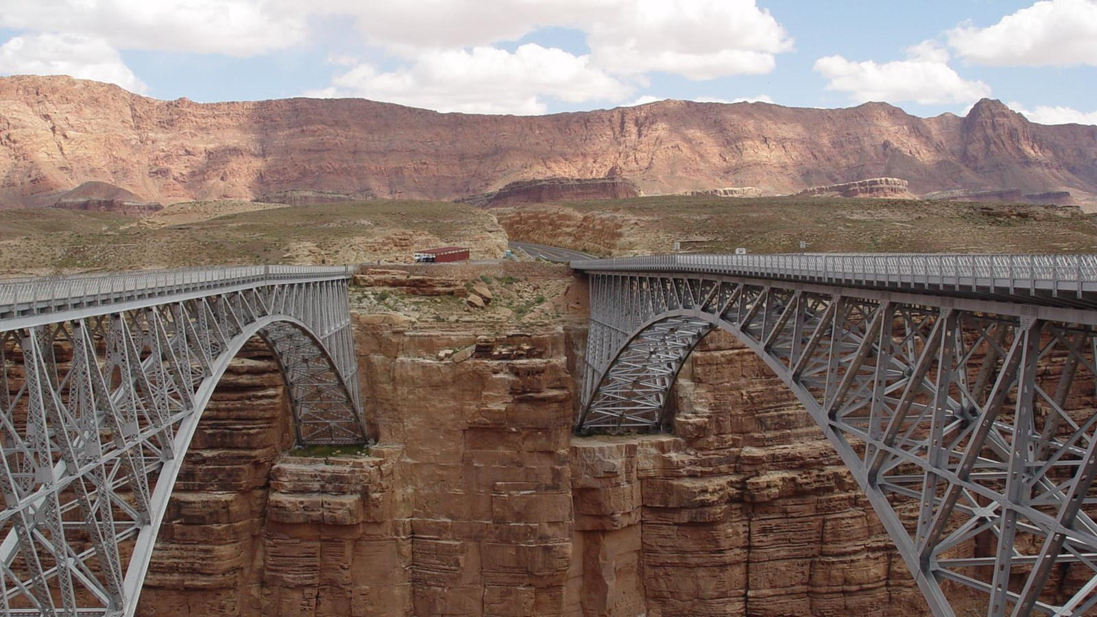 Two steel bridges span a canyon. The bridges are made for cars to cross the canyon.