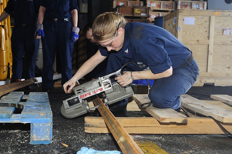 A portable bandsaw being used to cut a piece of angle.