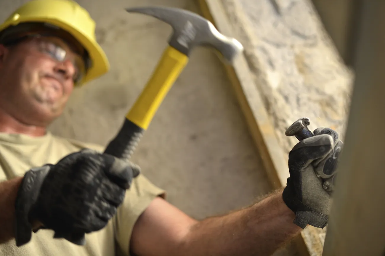 A man is hammering a chisel that has an extremely mushroomed head.