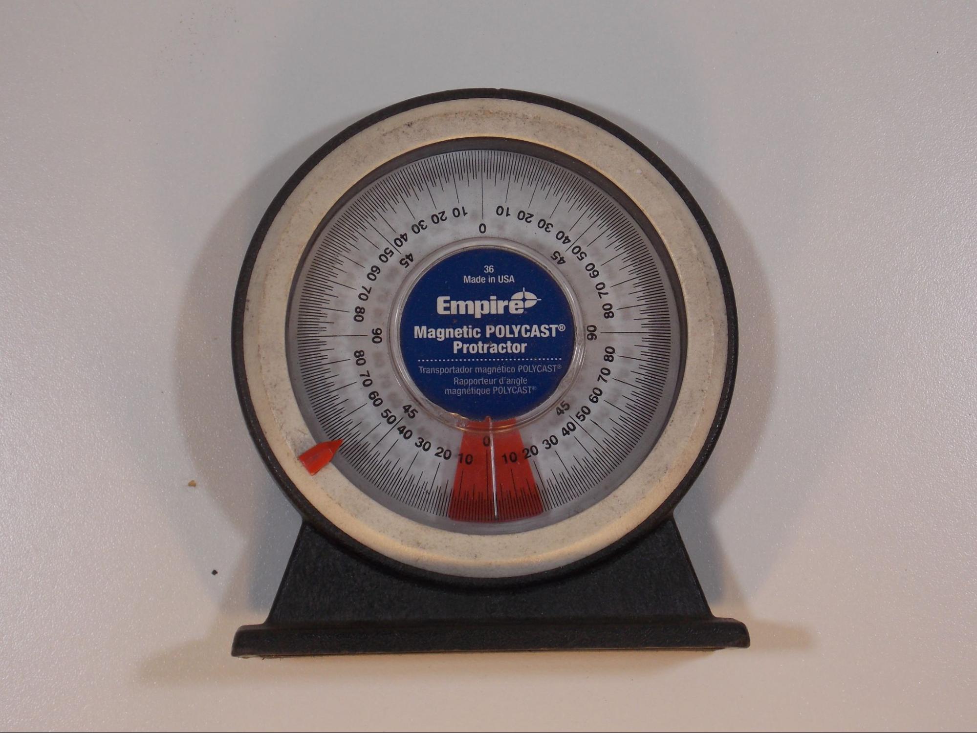 An angle finder, which is a circular dial with a flat base on one side. A pointer in the dial moves to indicate the angle of a surface with reference to the base. The dial has a 360 degree scale.