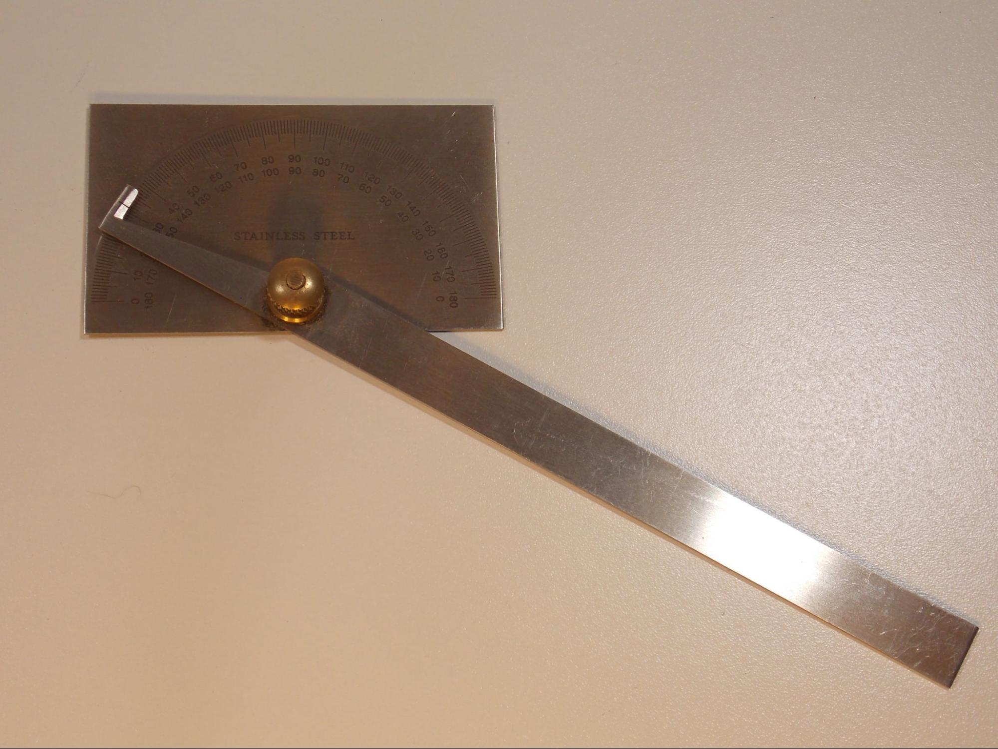 A steel protractor, which is made of a flat steel rectangle with a 180 degree scale etched onto the face in the shape of a half circle. A long flat steel arm is screwed into the rectangular piece, with the pivot point at the center of the scale so that a pointer on the short end of the arm can swing back and forth across the face of the scale in order to show the angle measurement.