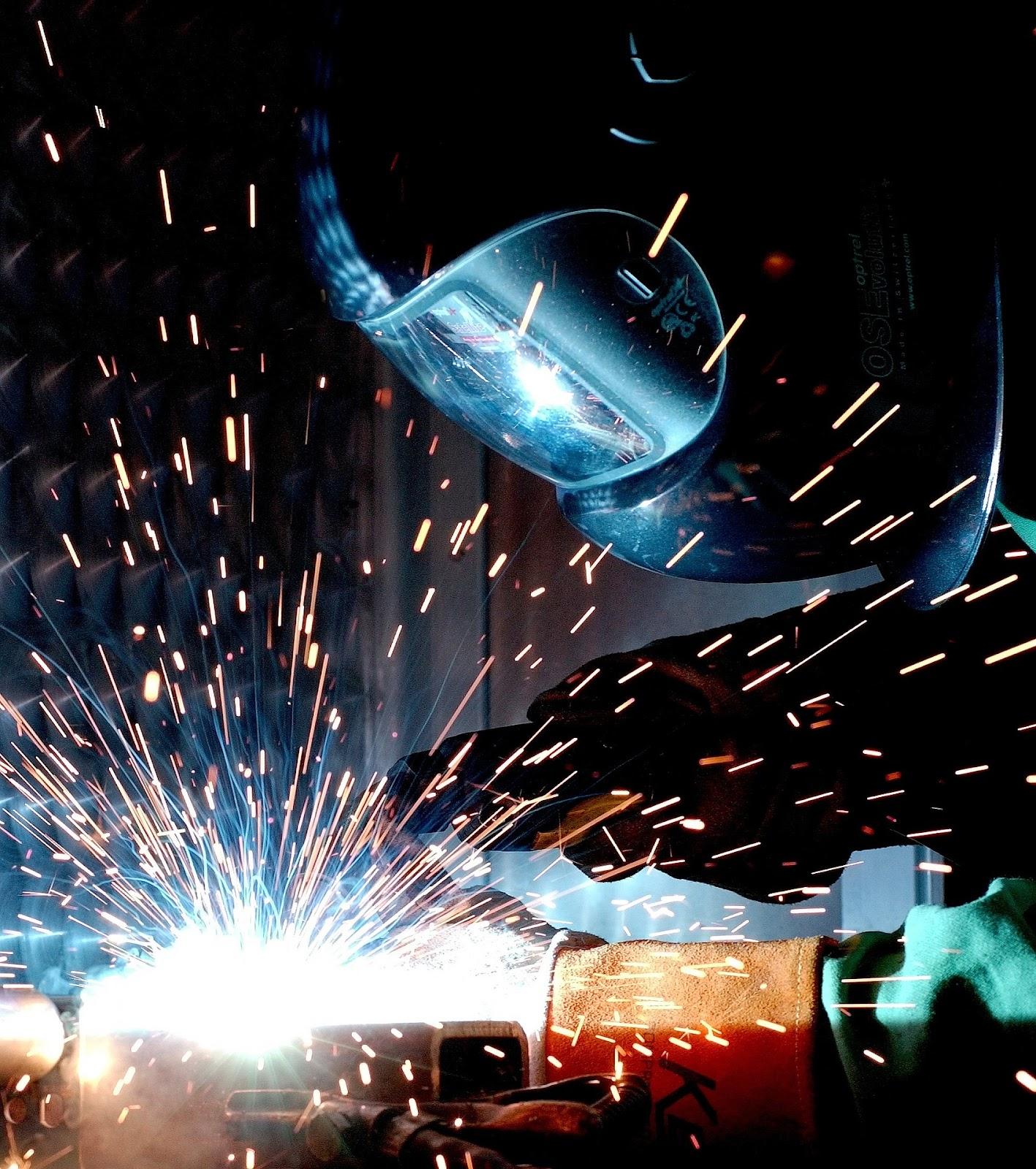 A welder performs wire feed welding with many sparks in the air.