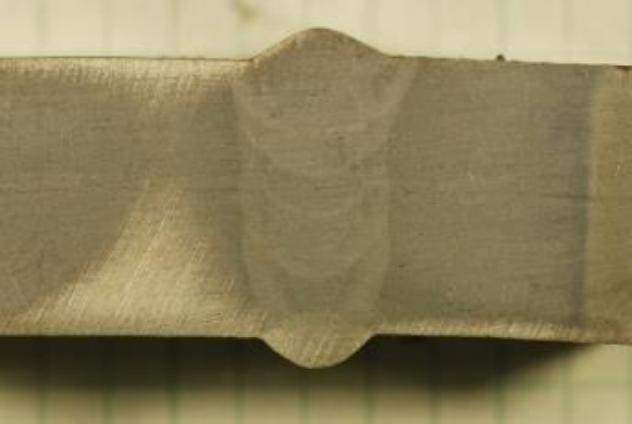 Macroetch of a weld joint under shop lighting. Two pieces of metal are joined together and a cross-section has been made. The weld bead can be seen from the inside showing the beads that were made as the welder welded.