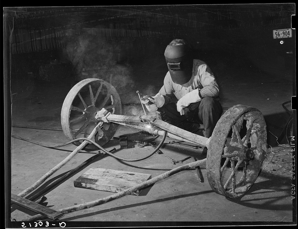 Welder welding an axle of a agricultural piece of equipment