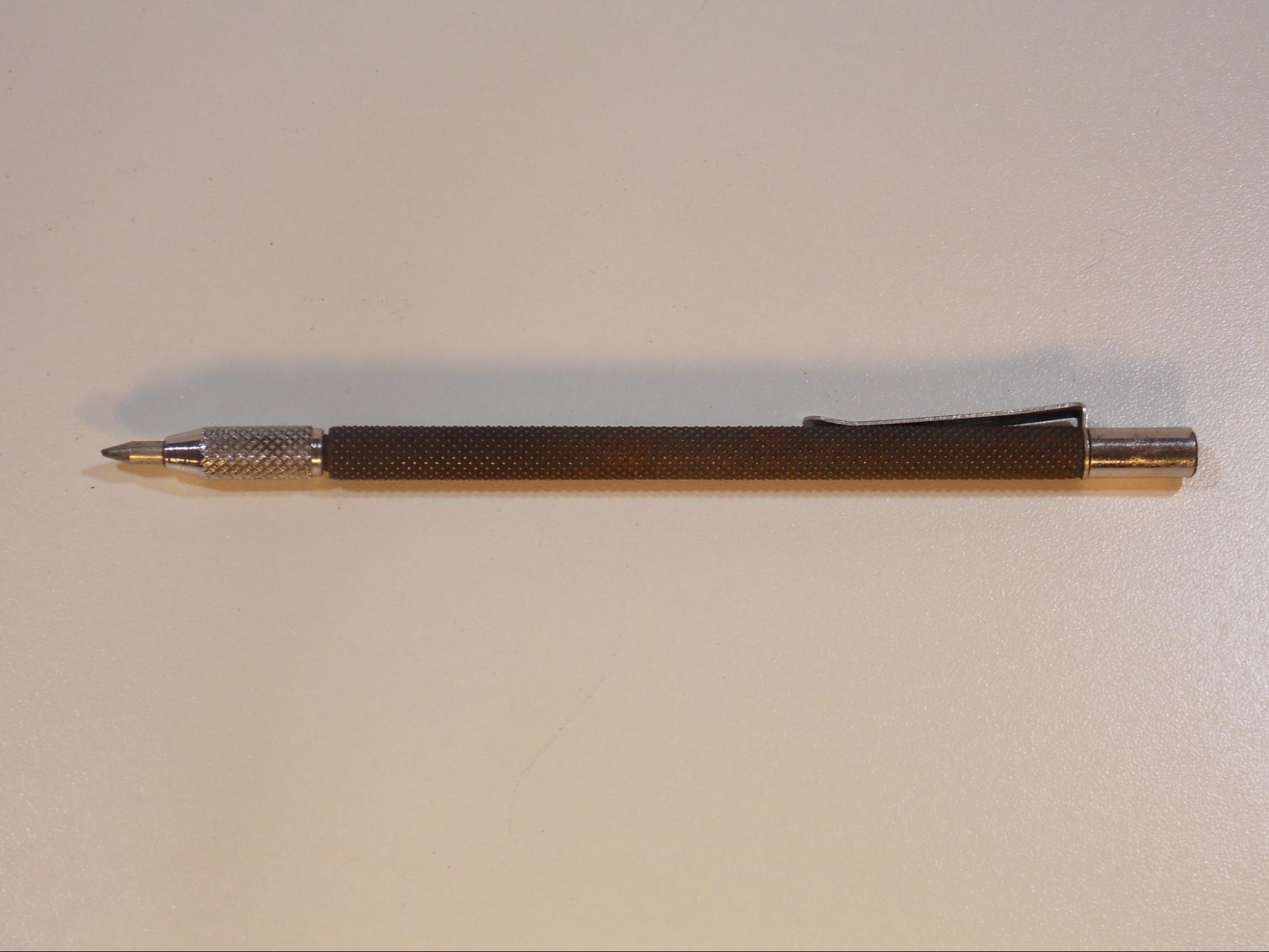 A metal scribe, which is pen-shaped but has a hardened metal point meant to scratch a mark into the work surface.