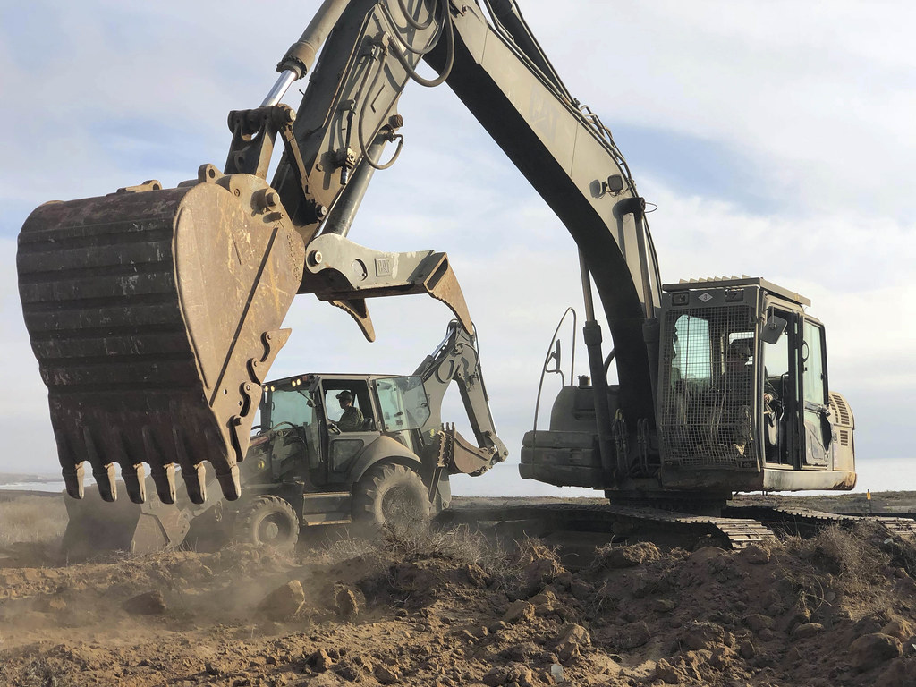 An excavator raises its bucket while digging.